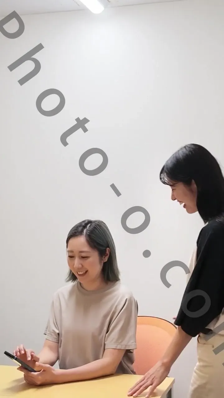 Two performers smiling during a phone-centered scene from the production preview; Photo-o.com watermark retained